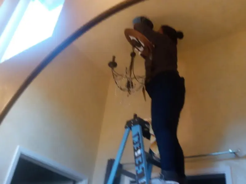 Electrician installing a chandelier in a Atascocita residence